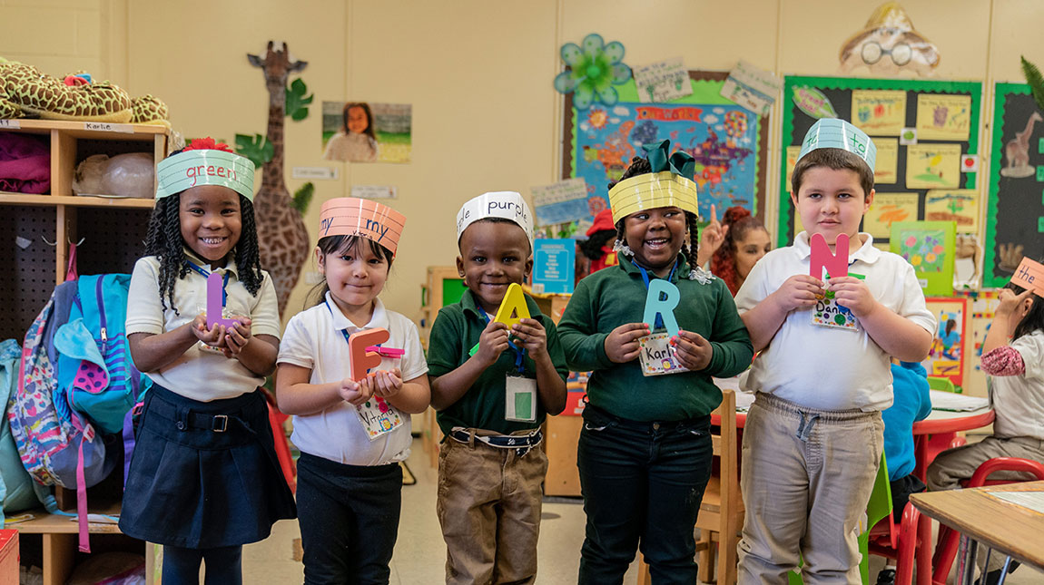Pre-K students holding letters that spell the word, learn