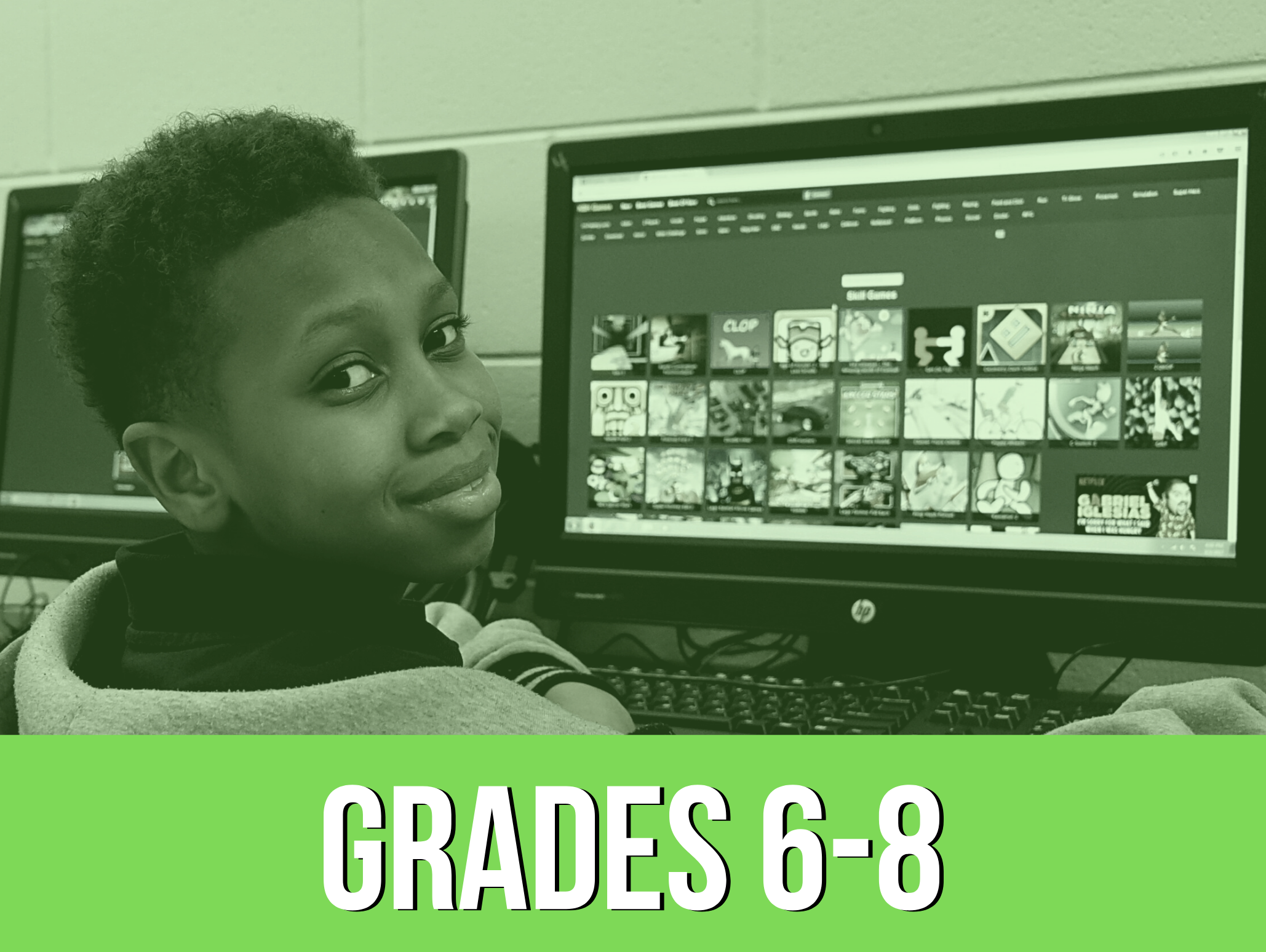 Boy in middle school sitting in front of computer and smiling at the camera