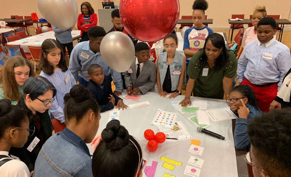 Group of students and teachers standing around table